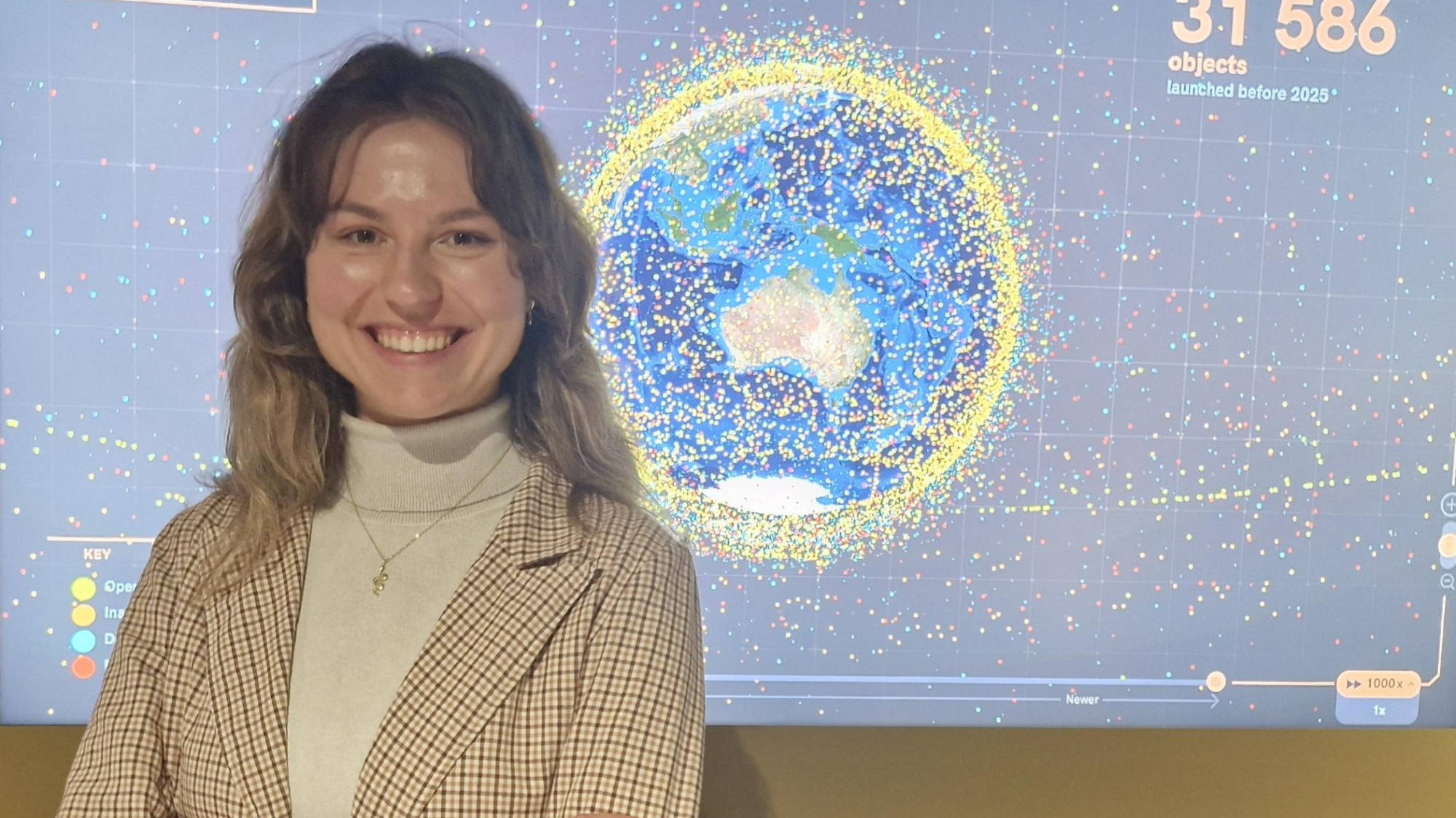 Young woman stands smiling in front of space backdrop