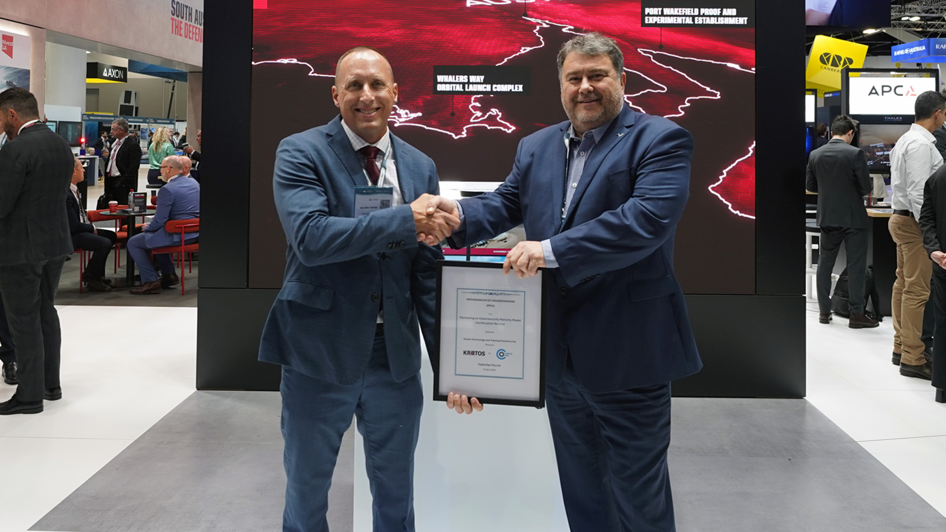 CyberOps landmark partnership with US-based Kratos Cybersecurity Services Two people shaking hands and holding a certificate ahead of a landmark partnership announcement