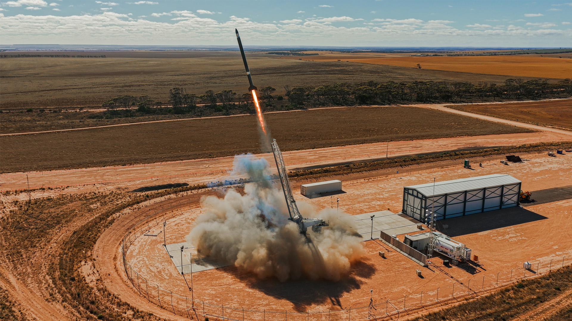 Red earth rural Australian backdrop, a rocket launches from the launch pad