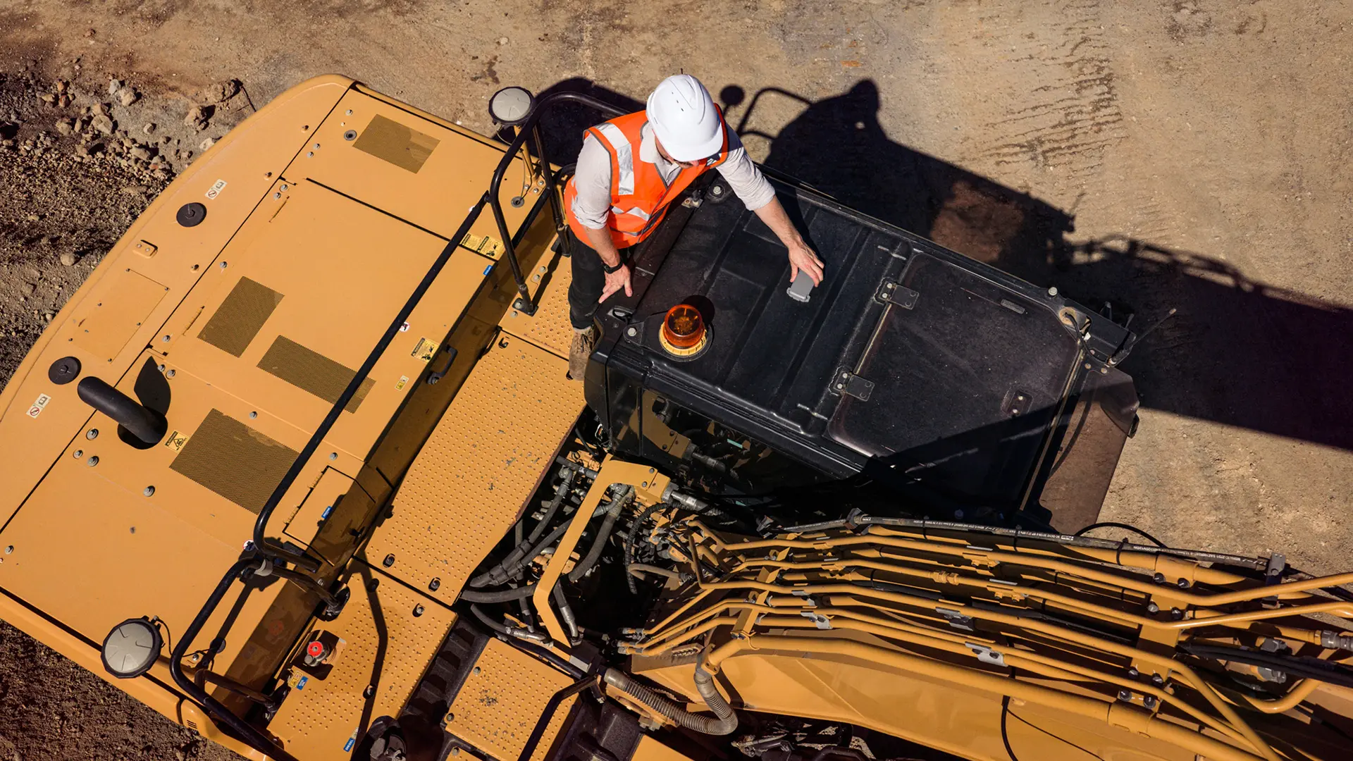 Myriota AssetHawk Image 2 copy Overhead shot, a man attaches an electronic device to the top of an earth mover