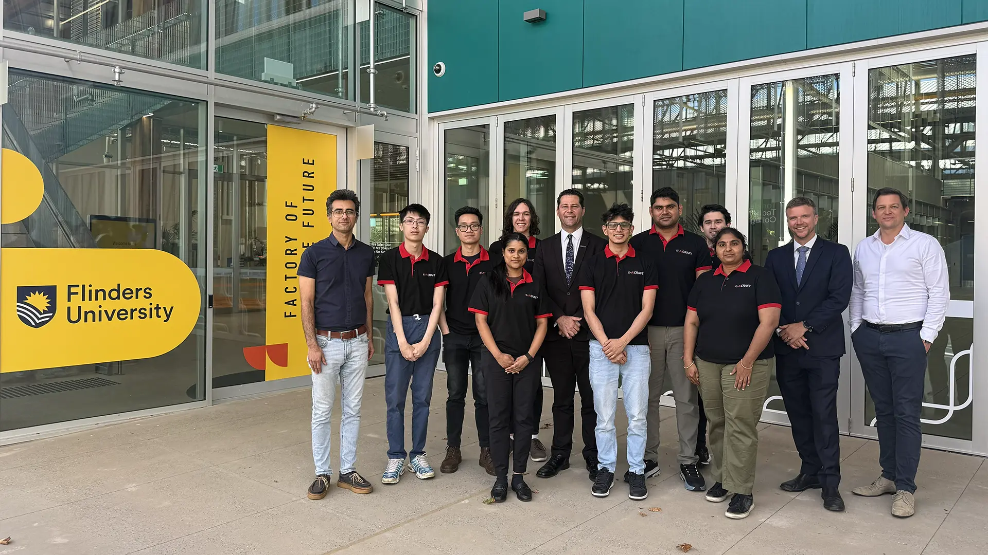 A group of people standing in front of the Flinders University's Factory of the Future.