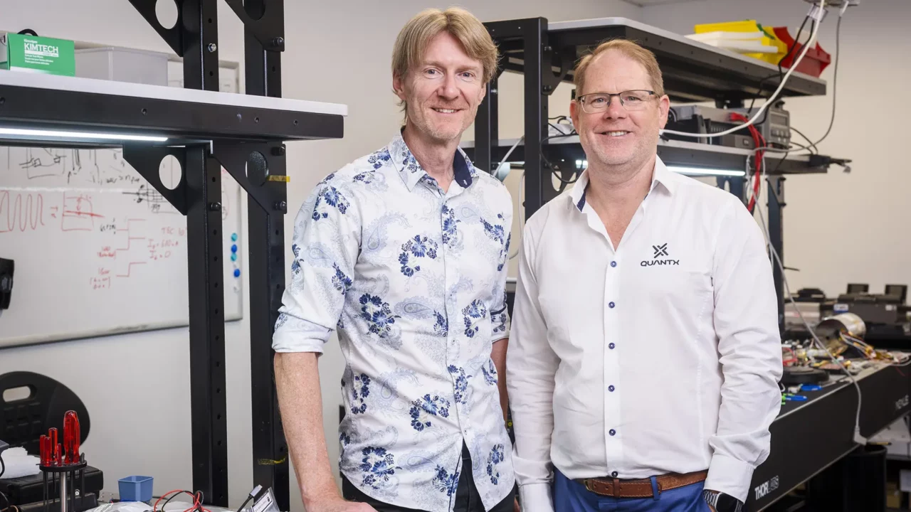 Two men standing in a lab smiling at a camera