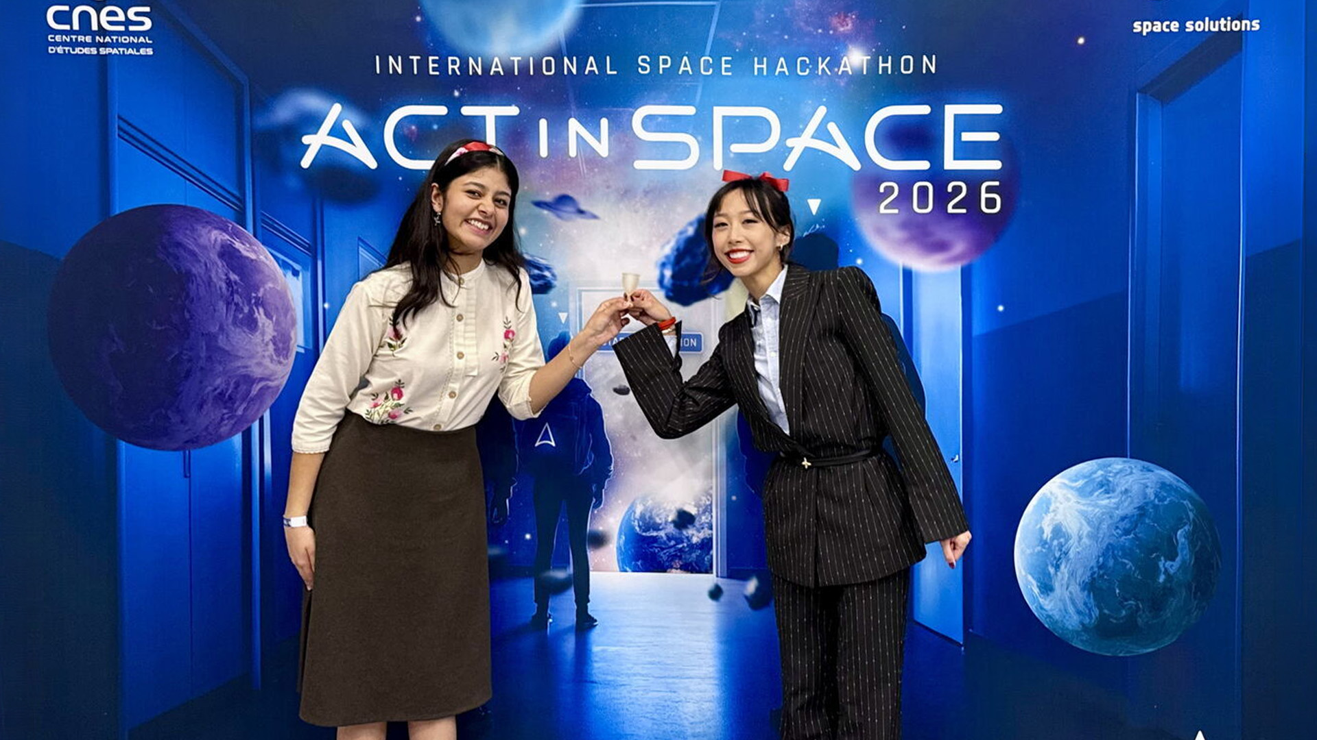 Two women standing in front of a bright space themed backdrop