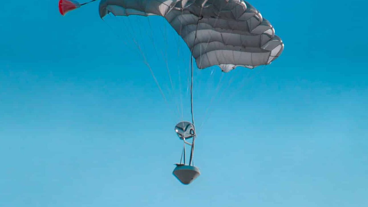 A capsule with parachute falling through the sky.