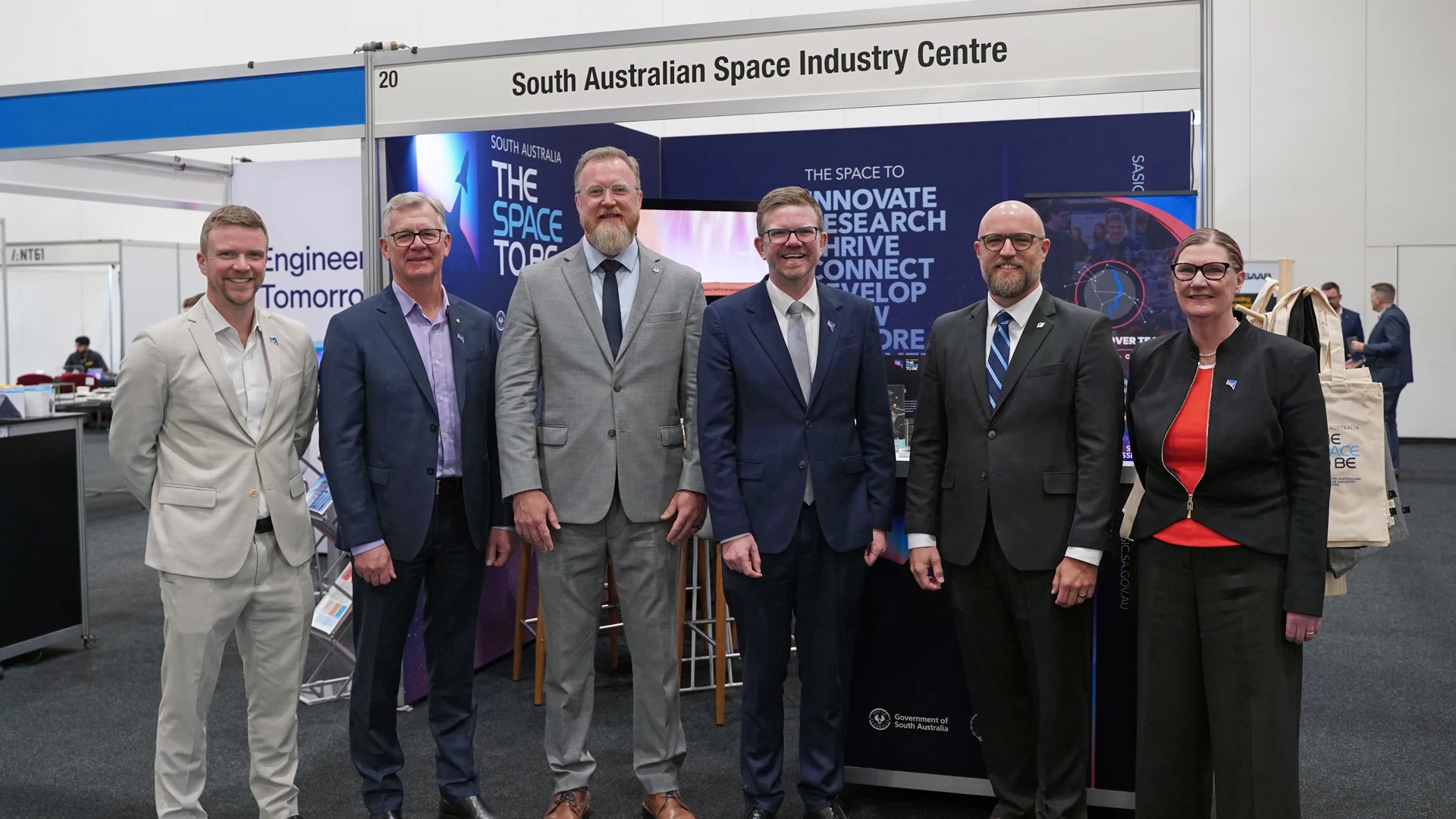 Group of high level professionals standing in front of a booth at a conference