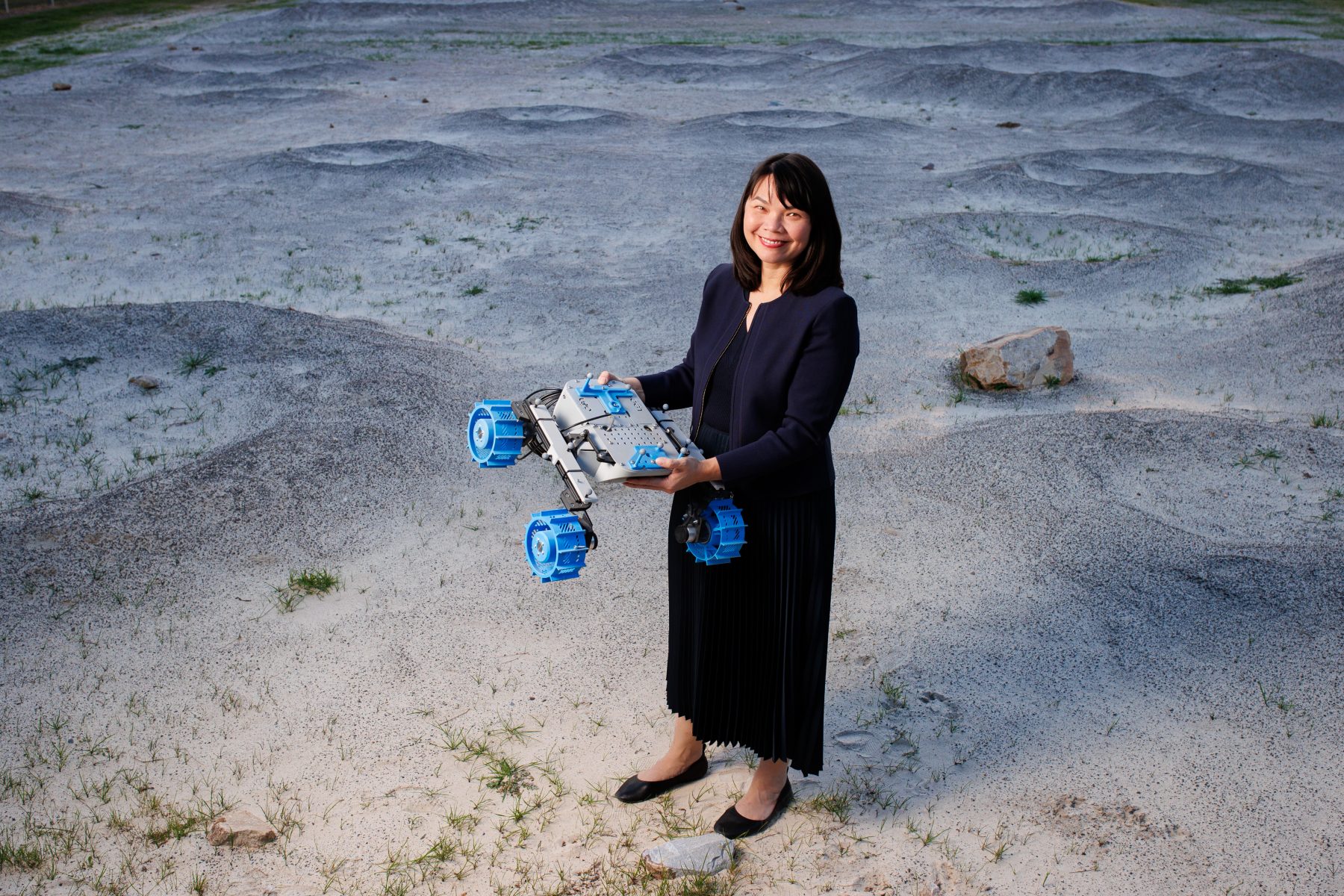 Lady holding a lunar rover while standing on sand