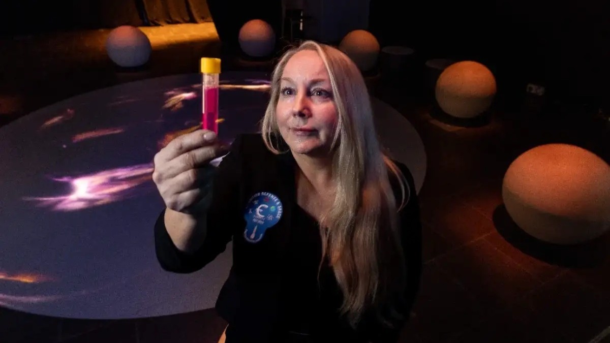 Woman looking at a test tube filled with red liquid